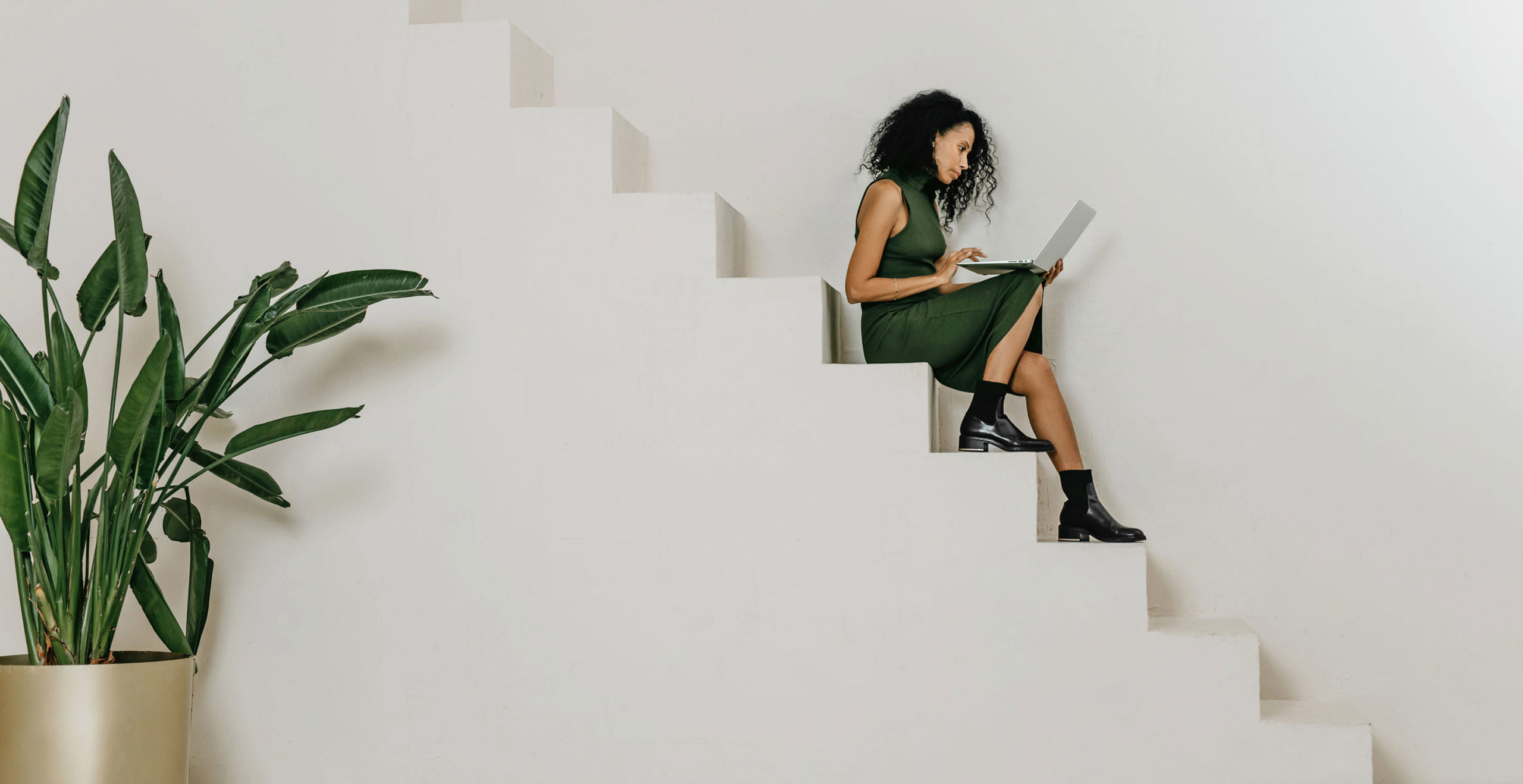 A young entrepreneur sitting on stairs while working on her laptop
